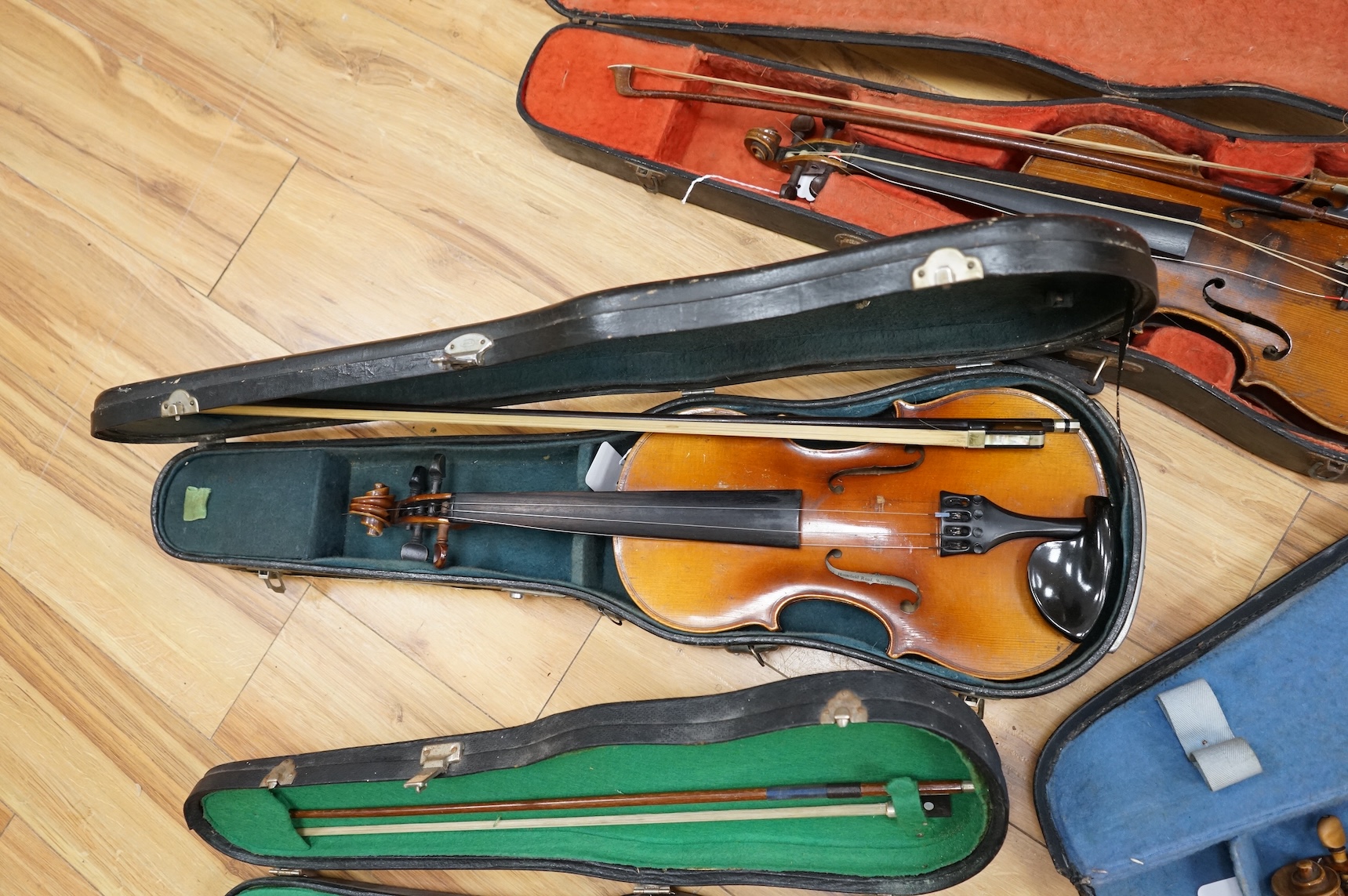 Five cased 20th century violins, including; a German violin, two Czech violins, a three-quarter size violin with a label for Bienfait, and a Romanian quarter size violin, all in cases or the remains of cases.